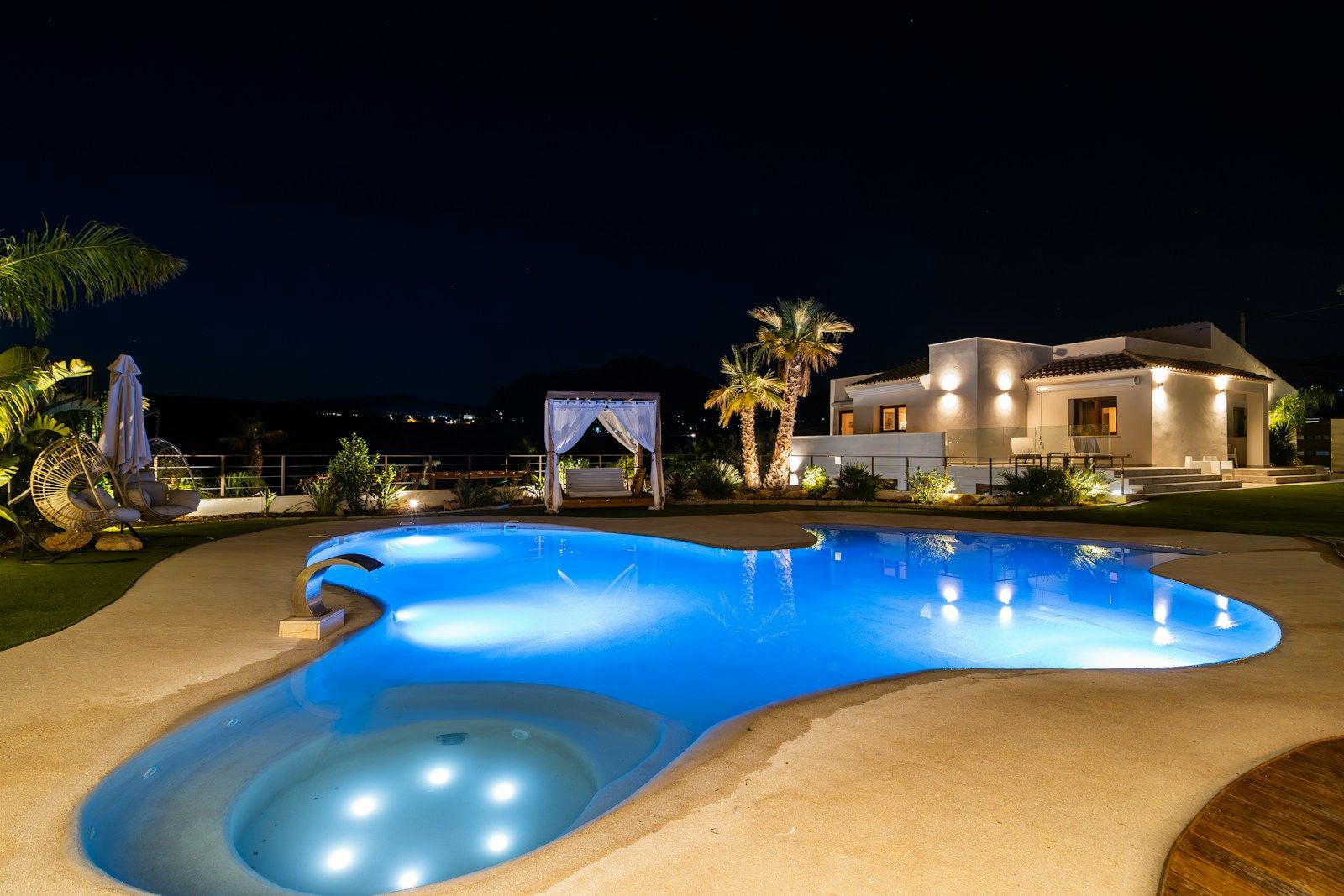 Freeform pool with underwater lighting at night — design inspiration (stock photo)